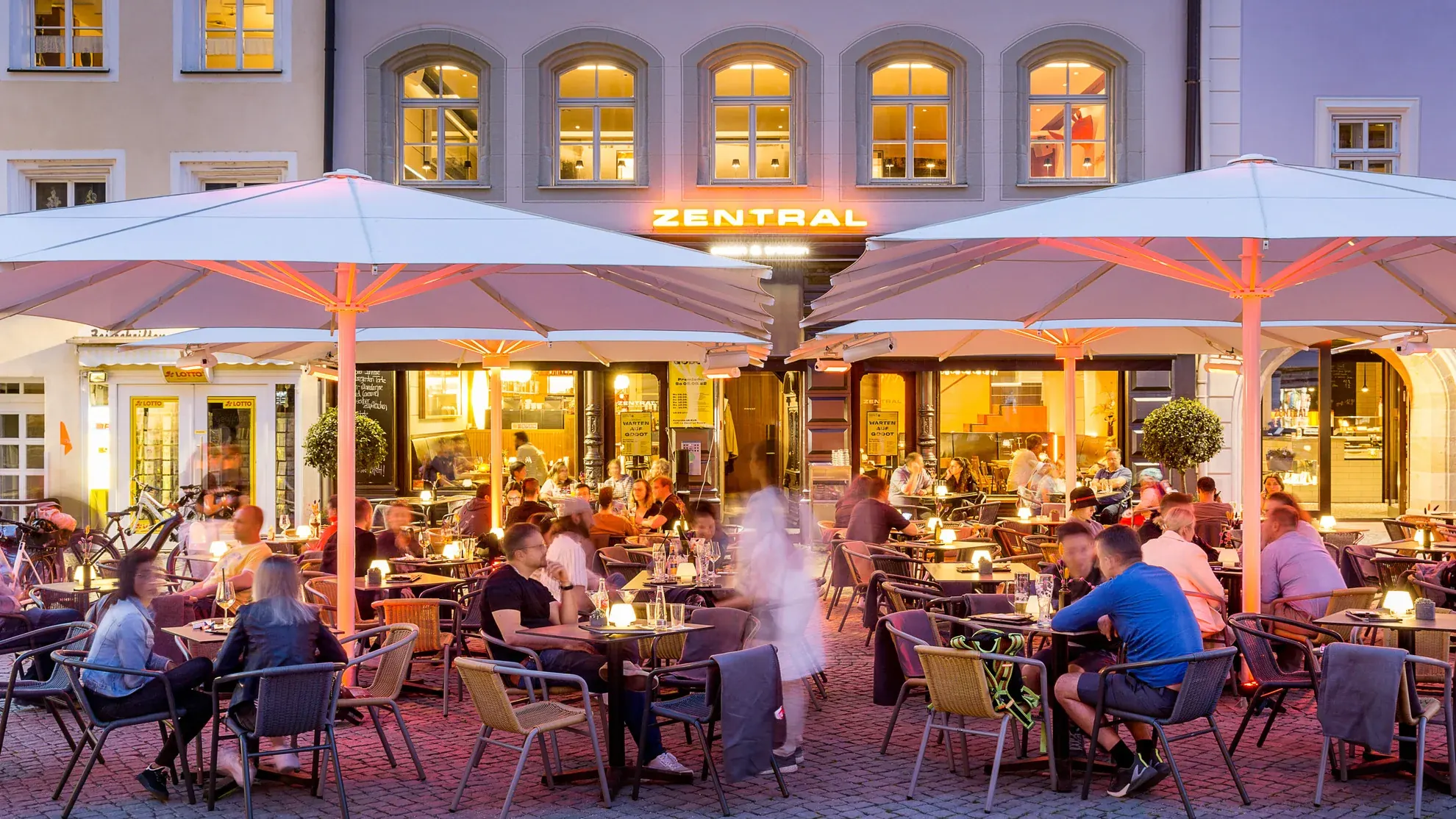 ZENTRAL am Amberger Marktplatz zur blauen Stunde — beleuchtete Fassade und volle Terrasse
